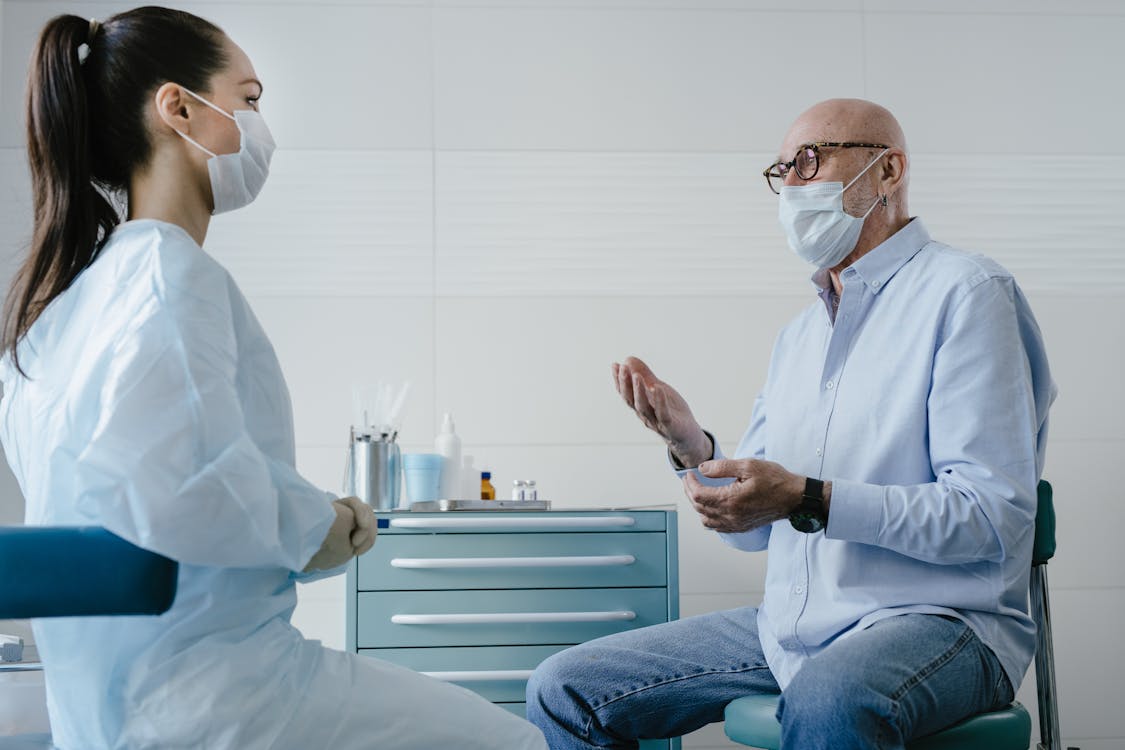 Paciente idoso conversando com médica geriatra em consultório