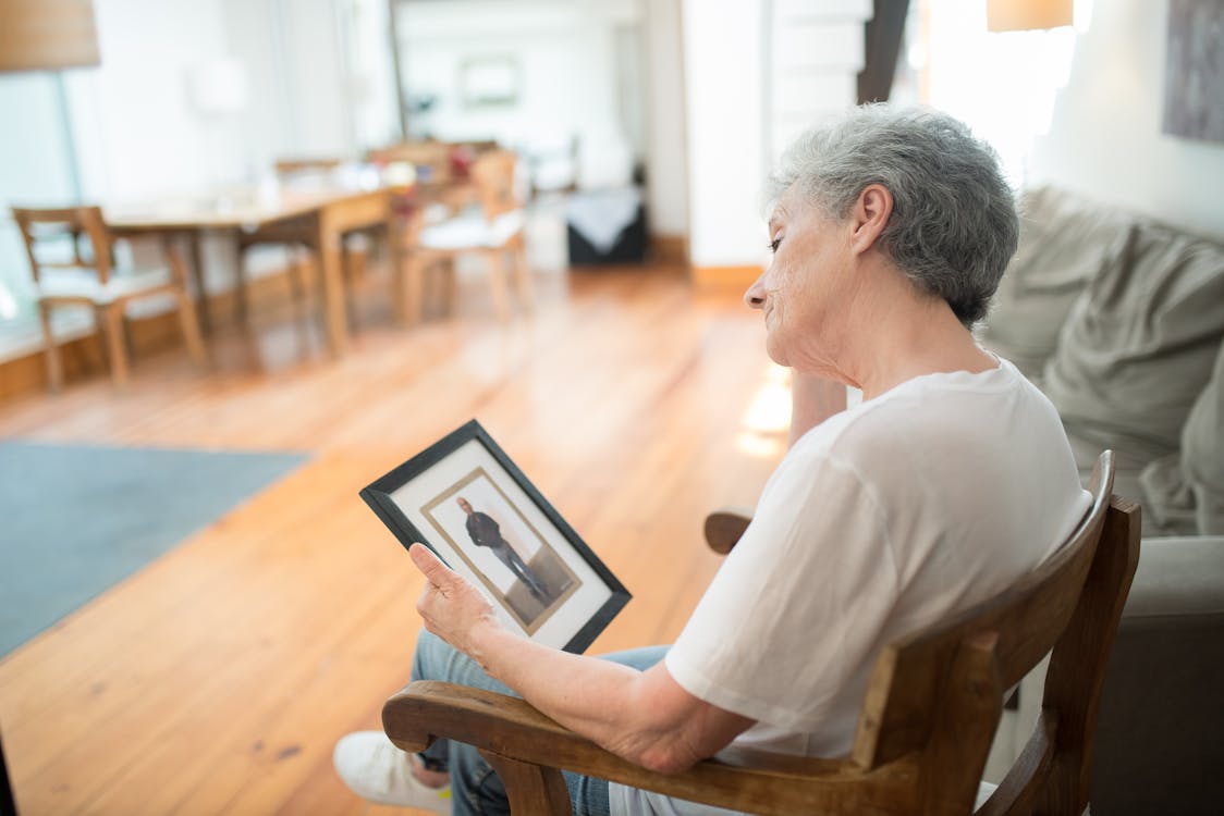 Idosa triste sentada olhando para foto de família - sinais de depressão em idosos